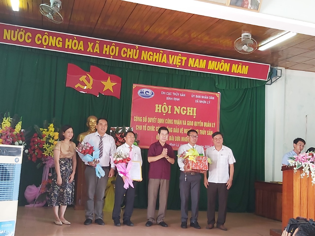 Ông Nguyễn Tiến Dũng – PCT thường trực UBND thành phố Quy Nhơn trao Quyết định và tặng hoa cho Tổ chức cộng đồng xã Nhơn Lý (người thứ 4 từ trái sang) (Medium)